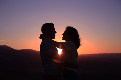 Pareja abrazándose con el atardecer al fondo